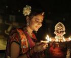 Femme à genoux avec une lampe à l'huile à la main dans la célébration de Diwali