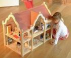 Fille jouant avec une poupée et une maison de poupée avec des meubles 