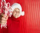 Enfant avec un chapeau de Père Noël et des cannes de bonbon à la main
