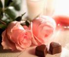 Deux roses rose avec deux en forme de coeur chocolats